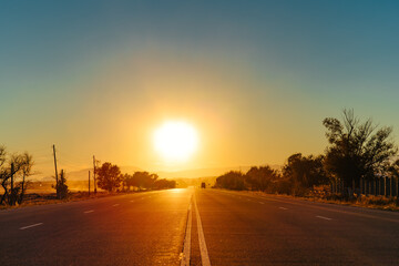 Two-lane road with sunset on the horizon