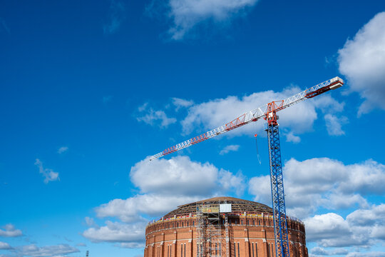 Industrial architecture at a construction site shows a crane beside a building in development as sky and cloud suggest steady progress