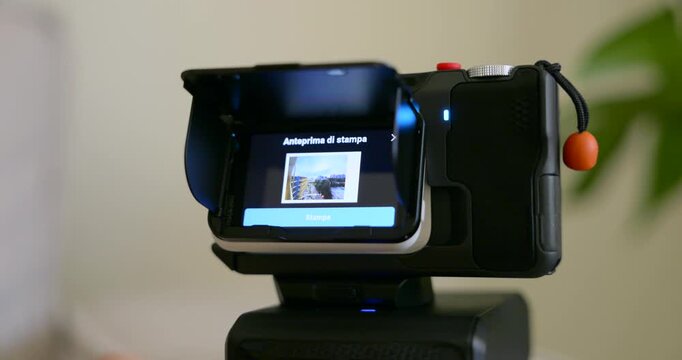 Close-up of hands swiping through footage on an action camera flip screen mounted on a tripod indoors