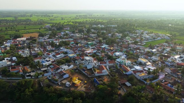 Aerial view of a South Indian rural village surrounded by lush green agricultural fields, coconut trees, and farmlands. Traditional houses, peaceful countryside life, and scenic village landscape.