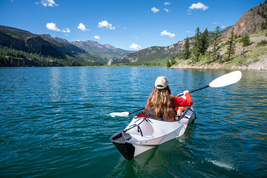 Brunette female kayaker on scenic Colorado Mountain lake