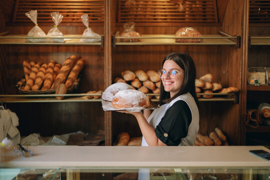 Female baker presenting fresh baked bread in shop
