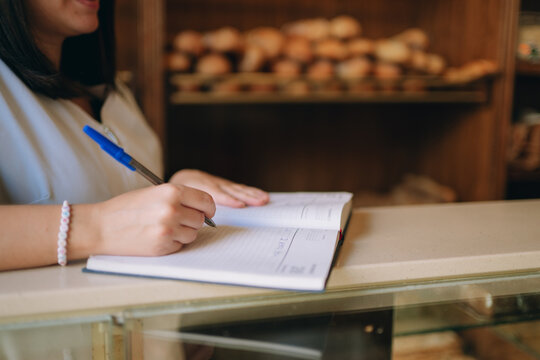Woman writing in notebook planning bakery business tasks