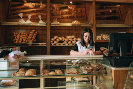 Female baker using smartphone creating content in bakery