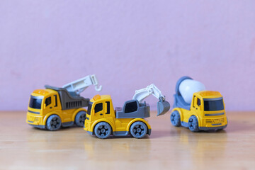 Group yellow mechanical construction mini toy truck put on wooden table a plaything for kid learning about construction site work and logistic work selective focus at toy crane truck