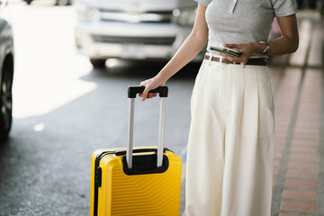 A traveler pulls a bright yellow rolling suitcase along a tiled walkway, capturing a modern travel lifestyle, minimal fashion, and mobility concept in an outdoor transit setting. © Worawi