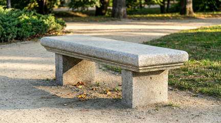 Stone bench seat in a park surrounded by greenery and pathways  