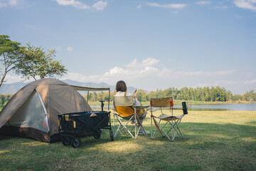 asian couple fun happy and relax with camping and picnic at side of lake with mountain background