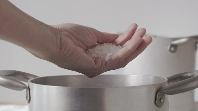 Adding salt into a grey pan
