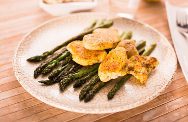 fried chicken breast pieces with asparagus on white plate