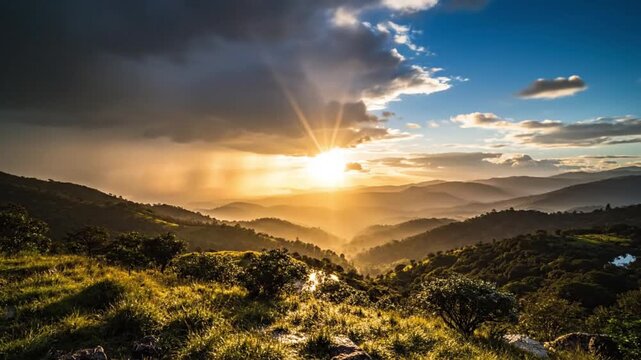 The video captures a breathtaking mountainous landscape at either sunrise or sunset, showcasing a dramatic interplay of light and atmosphere. Golden sunbeams pierce through heavy, dynamic clouds, cast