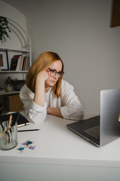 Overwhelmed employee with eyeglasses procrastinating at desk in office