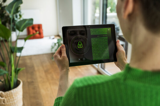 Person using smart home security app on tablet in modern living room