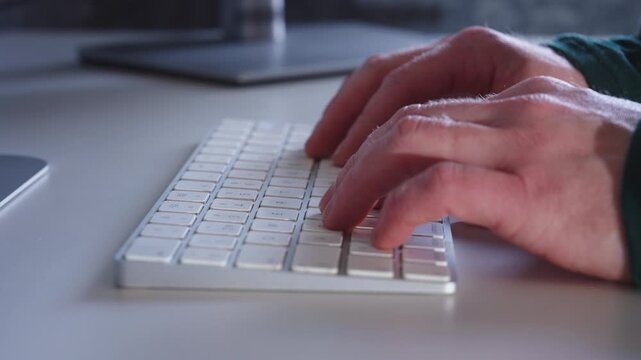 Hands resting on computer keyboard at modern home office desk