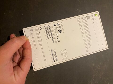 Palma, spain, january 20, 2026, hand opening pull tab on white iphone 17 pro max retail box packaging during unboxing process