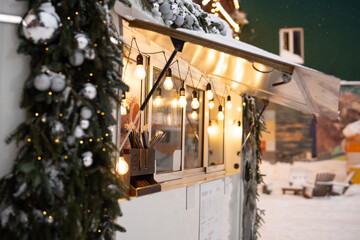 Cozy street cafe wagon at lively city square decorated with christmas lights and fir tree garland...