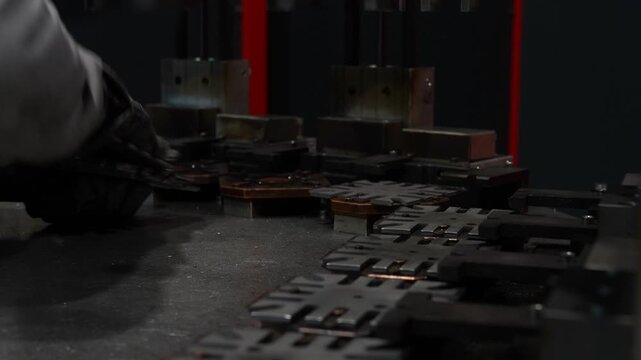 Manual manufacturing process showing worker placing metal washers in machine as part of precise production step, focused on accurate positioning, controlled handling and consistent mechanical workflow