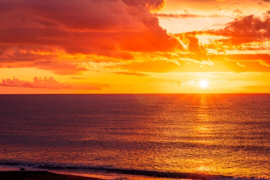 Dramatic seascape of sunset or sunrise sky with clouds during morning or evening. Dramatic sunset over the sea with orange clouds and sun above ocean water