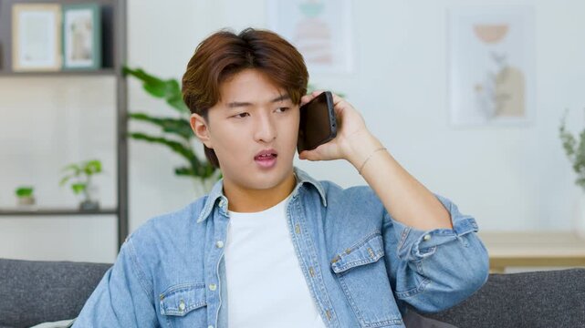 Frustrated Young East Asian Man Having An Angry Phone Conversation