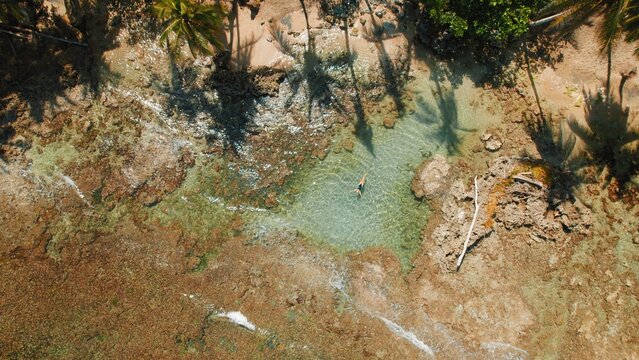 Solo traveler woman floating in tidal pool by palm beach Playa Cocles in Costa Rica.