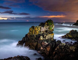 Rocky coast at dusk under a starry sky, with waves crashing