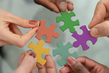 Diverse team hands joining colorful puzzle pieces for inclusion and equity initiative