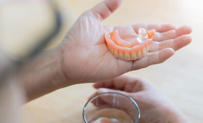 Rear view of flexible nylon denture on senior female hands. Removable dentures flexible