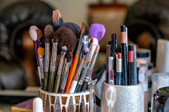 A bunch of makeup brushes sitting in a metal cup.