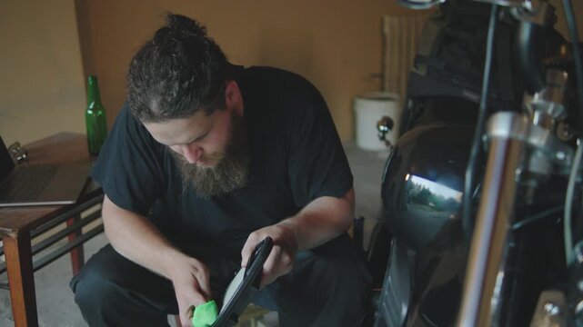 Mechanic working on motorcycle air filter inside garage with tools and laptop at hand during the afternoon