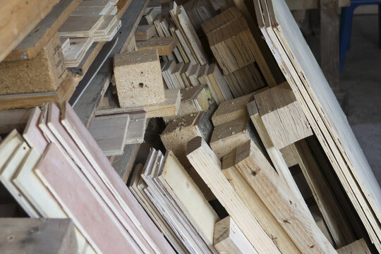 Pile of leftover wood scrap stack in carpentry workshop showing disorganized chaotic rustic texture of timber offcut waste material waiting for recycle or reuse project