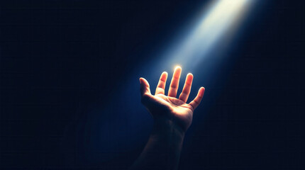A hand reaching up towards a divine beam of light on a dark background. Spiritual concept of hope, faith, and salvation. Asking for help or guidance
