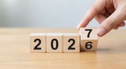 Naklejka premium Hand Flipping Wooden Block to Change Year from 2026 to 2027 on Wood Table