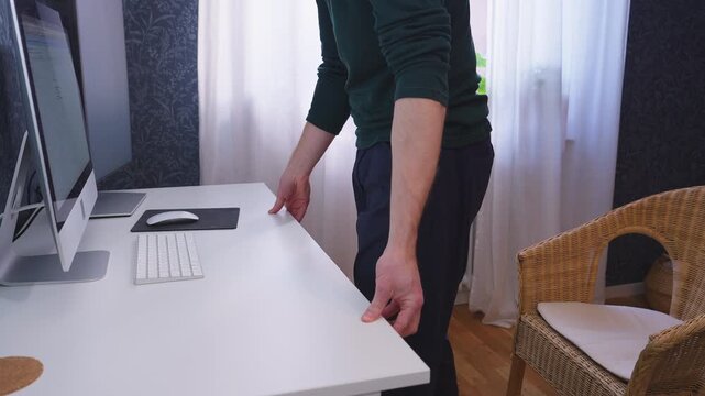 Raising adjustable desk and standing up at home office workstation