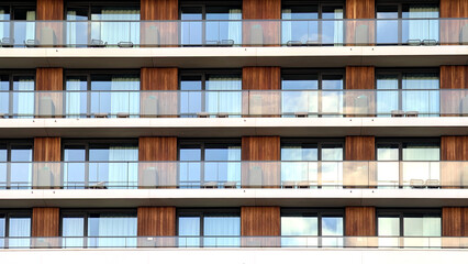 Modern building facade with windows and balconies during the day with clouds in the background. Pattern. Geometric clear building design