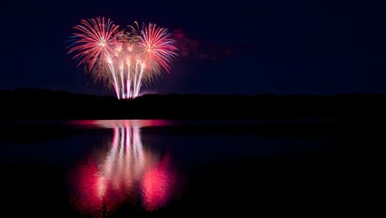 Vibrant fireworks display reflected in calm water at night