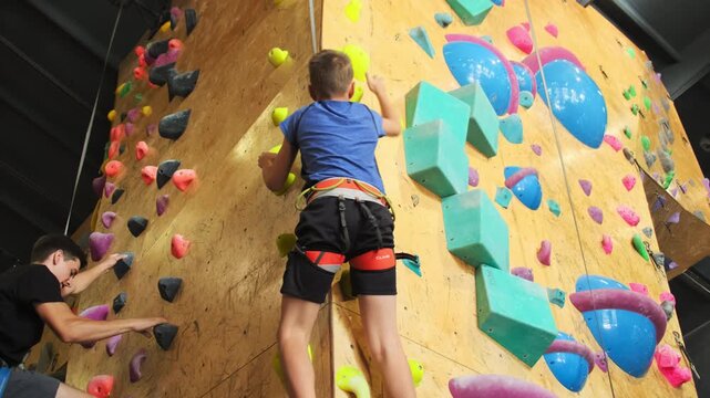Skilled trainer educates beginner athlete correct methods of climbing. Boy learns climbing up correctly watching trainer slow motion