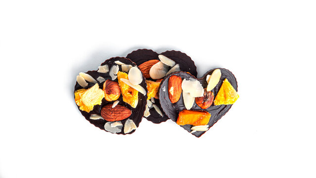 Raw heart shaped chocolate with dried fruits and nuts on a white background. High quality photo