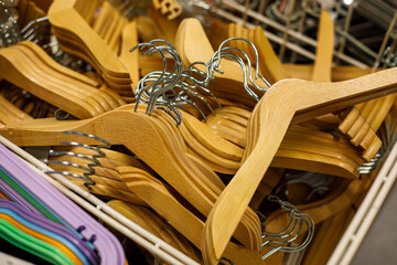 Pile of wooden clothes hangers with metal hooks in retail store basket, natural wood wardrobe accessories background, organized storage and shopping concept