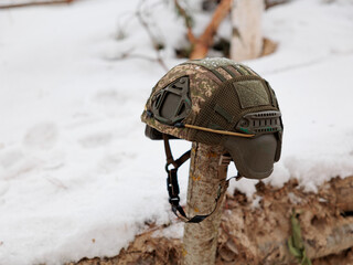 Obraz premium Military camouflage helmet in the snow. Concept of war in winter time