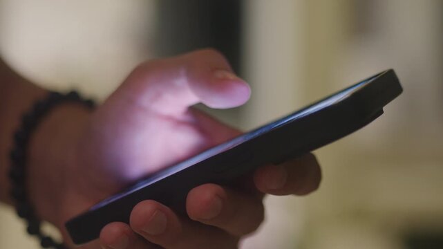 Close up scrolling smartphone in evening, closeup of hand and phone with evening ambient lighting, detailed shot showing finger tapping smartphone screen with blue glow during night hours