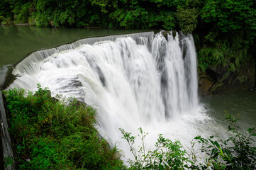 Wide view of Shifen Waterfall in Taiwan, showcasing powerful cascading water, lush surroundings, and dramatic natural scenery at one of the country&rsquo;s most iconic waterfalls.

