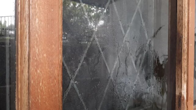 Close up of spraying water on window pane and wiping with rubber squeegee