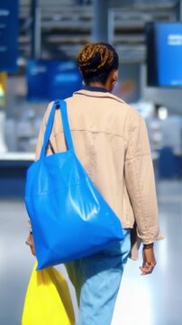 Urban Life: A Young Woman Walking Through a Modern Space with Colorful Tote Bags, Capturing the Essence of City Fashion and Everyday Moments