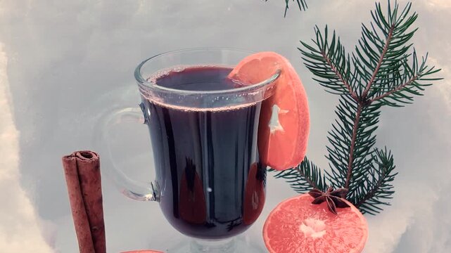 Mulled wine in a transparent glass mug, orange, spices against a snowy backdrop, winter composition.