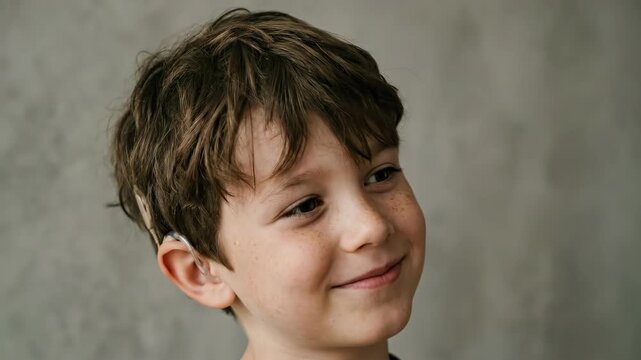 profile of happy caucasian boy wearing cochlear implant. child with hearing aid smiling. deafness, disability and medical technology concept. healthcare campaign.