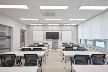 Modern classroom interior with rows of white desks and digital board