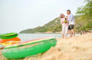 Fototapeta premium In holiday, Senior couple standing together and smiling while holding fruit