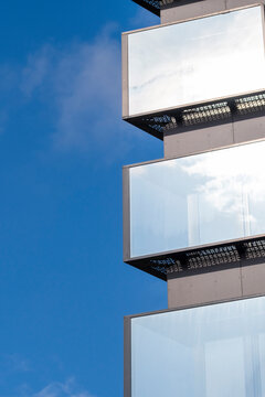 Modern urban architecture building facade with glass balcony and sky reflection showing minimal geometry and clean contemporary exterior