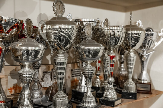 A crowded trophy shelf featuring numerous silver awards, many topped with "1" medallions, symbolizing first-place achievements in various competitions
