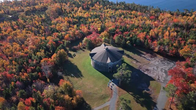 Aerial Footage Shows Ancient Stone Tower Surrounded By Orange And Yellow Leaves In A Quiet Park In Halifax At Dawn. Golden Hour Highlights The Historical Charm.